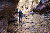 USA, Utah, Springdale, Zion National Park, Ältere Frau überquert Fluss beim Wandern in den Bergen