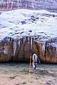 USA, Utah, Springdale, Zion National Park, Ältere Frau überquert Fluss beim Wandern in den Bergen