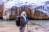 USA, Utah, Springdale, Zion National Park, Senior woman crossing river while hiking in mountains
