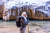 USA, Utah, Springdale, Zion National Park, Ältere Frau überquert Fluss beim Wandern in den Bergen