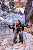 USA, Utah, Springdale, Zion National Park, Älteres Ehepaar überquert Fluss beim Wandern in den Bergen