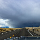 USA, Nevada, McDermitt, Highway führt auf Gewitterwolken am Horizont zu