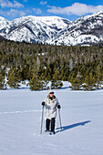 USA, Idaho, Sun Valley, Senior woman wearing snowshoes hiking in mountains