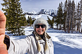 USA, Idaho, Sun Valley, Ältere Frau macht Selfie in verschneiten Bergen