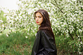 Portrait eines Teenagers (16-17) vor einem blühenden Apfelbaum