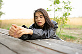 Portrait of teenage girl (16-17) leaning on picnic table