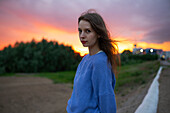 Portrait of beautiful woman standing in field at sunset