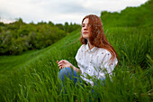 Portrait of serious teenage girl (16-17) sitting on grass