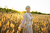 Portrait of woman standing in field at sunset