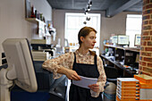 Frau hält Papier bei der Arbeit in einer Druckerei
