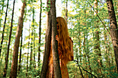 Young woman touching tree in forest