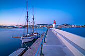 Blick auf Hafenleuchtturm und Segelschiff in der Abenddämmerung, UNESCO-Weltkulturerbe, Ibiza-Stadt, Eivissa, Balearen, Spanien, Mittelmeer, Europa