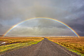 Ein Regenbogen überspannt eine Straße in der Landschaft bei Rif, Halbinsel Snaefellsnes, Westisland, Polargebiete