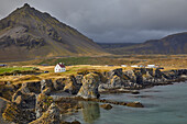 A classic view of the basalt lava cliffs on the coast at the village of Arnastapi, backed by the mountains of Snaefellsjokull, Snaefellsjokull National Park, Snaefellsness peninsula, west coast of Iceland, Polar Regions