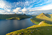 Wolken am Sommerhimmel über Bergen entlang eines Fjords, Eysturoy Island, Färöer Inseln, Dänemark, Europa