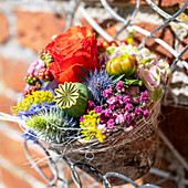 Colorful summer flowers in shabby clay pots on a wall shelf