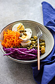 Bowl with boiled eggs, capers, olives, red cabbage, and carrots (Keto cuisine)