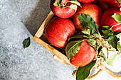 Wooden box with red apples on concrete table