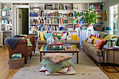 Wohnzimmer mit Bücherregalen, bunten Kissen und Pflanze