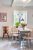 Hell gestrichenes Esszimmer mit Holzmöbeln und frischen Blumen