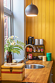 Small kitchen corner with sink and hanging lamp next to window