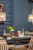 Set dining table with wooden chairs in front of blue wall