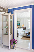 Bright country house interior with blue wall panelling and display cabinet