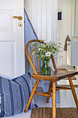 Country-style hallway with wooden chair and fresh flowers