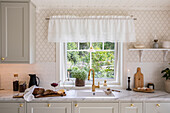 Country-style kitchen with light-colored tones and a view of the garden
