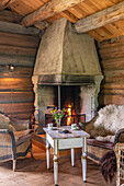 Rustic open fireplace with wooden furniture and furs in log cabin