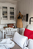 Landhausstil-Schlafzimmer mit weißem Schrank, Schneiderpuppe und Akzenten in Rot