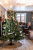 Weihnachtlich geschmückter Tannenbaum in Raum mit Holzfußboden