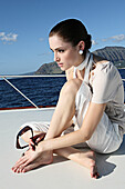 Young brunette woman wearing a light blouse and shorts on a boat