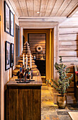 Rustic interior with wood panelling, candle holders and paper Christmas tree on a chest of drawers