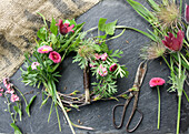 Kranz binden aus Küchenschelle (Pulsatilla), Vergissmeinnicht, Gänseblümchen (Bellis) und Birkenzweigen