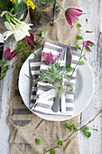 Table setting with striped napkin and bouquet of pasque flower (Pulsatilla)