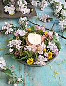 Wreath of apple blossoms and dandelions in baking tin, with candle