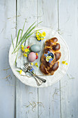 Easter plait with eggshell filled with cowslip and forget-me-not, with Easter eggs and cutlery