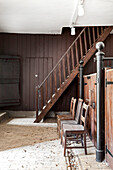 Alte Holztreppe und Holzstühle im Stall mit Backsteinboden