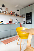 Modern kitchen with pastel green cupboards and yellow chair