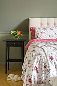 Floral pattern bed linen in bedroom with light grey-green wall