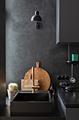 Modern kitchen with black sink, brass tap and wooden cutting boards