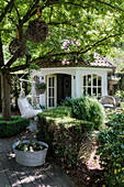 Gemütliches Gartenhaus mit Hängesessel und Zinkwanne unter einem schattigen Baum