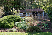 Horse stable with wooden fence in the garden in front of the forest edge in spring