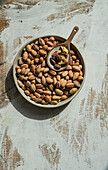 Organic pistachio nuts in the ceramic bowl on rustic wooden table