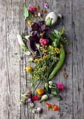 Herbs, edible flowers and colorful eggplant on a wooden base