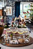 Festlich gedeckter Tisch mit Getränken, Snacks und Weihnachtsbaum im Hintergrund