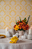 Autumnal bouquet of flowers and ceramic pumpkins on table