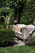 Wooden bench with cushions and furs in cozy garden corner