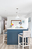 Kitchen island with rattan bar stools in a modern, brightly designed kitchen